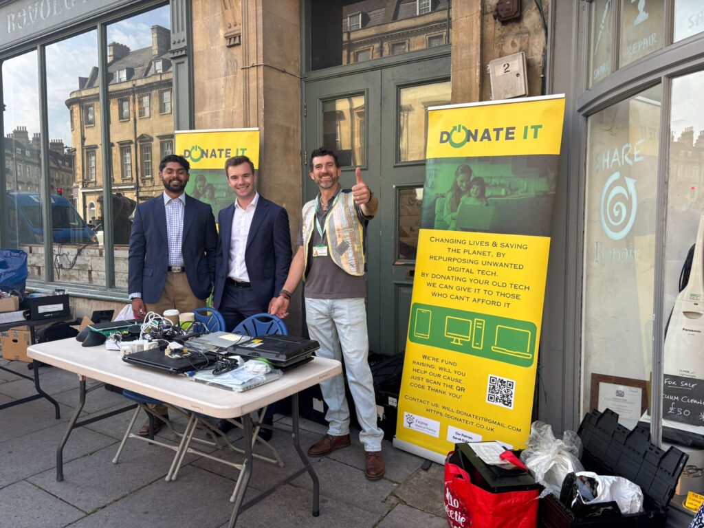 Tech Amnesty July | three men standing at a stall collecting tech donations, and smiling | phones now offered thanks to Donate IT