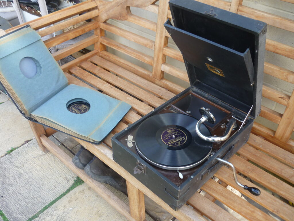 A Gramophone from the 1930s open on a bench, with a book of vinyl records open next to it